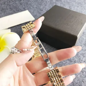 Gold metal watch strap detail showing pyramid studs and folding clasp mechanism close up view