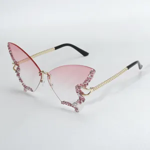 Close-up detail of trendy butterfly rimless sunglasses with pink gradient lenses and rhinestones.
