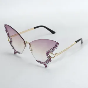 Detail shot of butterfly rhinestone sunglasses with gradient purple ocean lenses and chain temples.