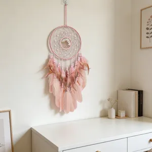 Détail de l'attrape-rêves rose montrant des plumes délicates et des perles tissées.