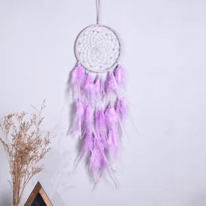 Detailaufnahme des handgefertigten lila Traumfängers Wandbehangs mit Federn und Perlen.