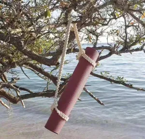 Handmade macrame yoga mat strap hanging on tree outdoors, durable cotton carrier rope.