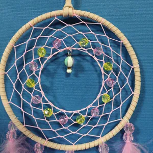 Pink dream catcher detail shot with cute beads and hot air balloon charm for room decor.
