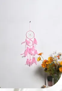 Vista detallada del atrapasueños rosa de plumas como elegante decoración colgante de pared.