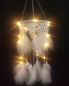 Weißer Spitzen-Feder-Traumfänger mit warmen LED-Lichterketten, Nahaufnahme der hängenden Dekoration.