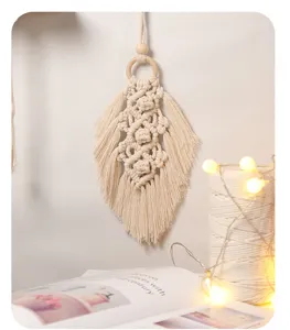 Detailansicht des handgefertigten Makramee Blatt Wandbehaengs aus Baumwolle mit Holzperlen und Licht.
