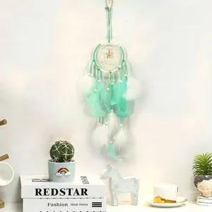 Vue détaillée de l'attrape-rêves vert menthe avec des plumes et des lumières pour déco.