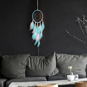 Gros plan du capteur de rêves artisanal à plumes bleues et blanches avec lumière LED.