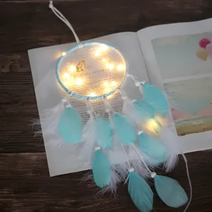 Vue détaillée de l'attrape-rêves bleu illuminé avec guirlande lumineuse LED, plumes et perles.
