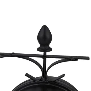 Detalle del pináculo superior de reloj de pared de hierro negro, elemento de soporte metálico.