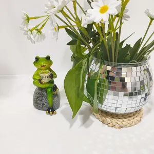 Vista detallada de la figura de rana de resina con taza y florero de bola disco de cristal.