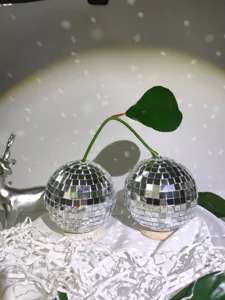 Detailed close-up shot of creative mirrored disco ball cherry ornament with green stem.