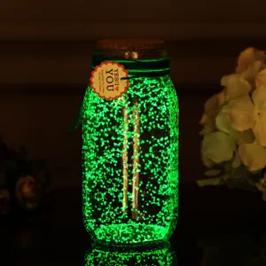 Glow in the dark luminous sand particles detail shot, fluorescent green pigment in glass jar.