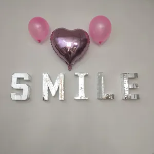 Detailed view of 3D mirror mosaic letters spelling smile with party balloons on wall decor.