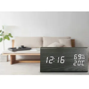 Close-up detail of a modern black wooden LED digital desk clock displaying time and temperature.