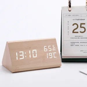 Wooden triangular LED digital desk clock close up showing time temperature and humidity.