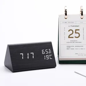 Wooden triangular LED alarm clock detail view with digital time, temperature and humidity.