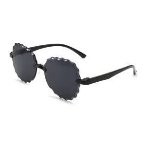 Trendy montuurloze zonnebril met zwarte bloemblaadjeslenzen, stijlvolle bril voor de zomer.