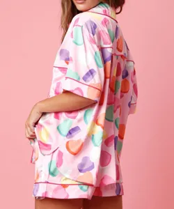 Women's pink satin pajama set featuring colorful heart print, short sleeve top and shorts.