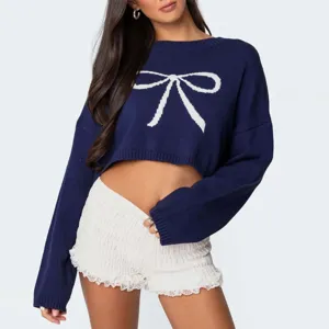 Detaillierte Nahaufnahme des stilvollen dunkelblauen Crop-Pullovers mit weißem Strickschleifen-Design.