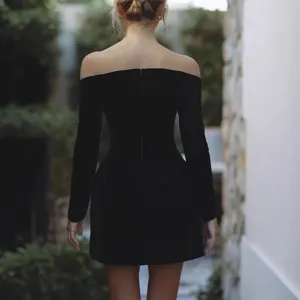 Vue détaillée de la robe courte noire en velours avec épaules dénudées et strass scintillants.
