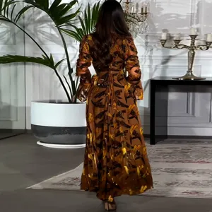 Elegante vestido largo de manga larga con estampado dorado y lazo en la cintura.