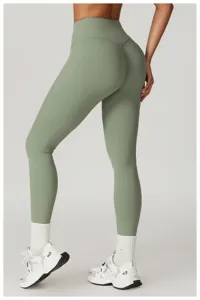 Leggings da yoga a vita alta scrunch butt in verde salvia, abbinati a calzini bianchi.
