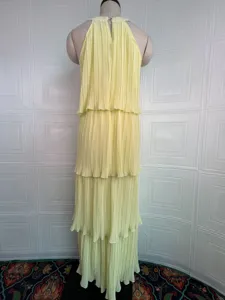 Detalle del vestido halter amarillo con volantes escalonados, diseño sin mangas elegante.