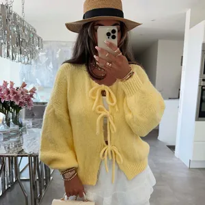 Detalle de cárdigan de punto, suéter amarillo con lazos elegante, textura suave y cómoda.