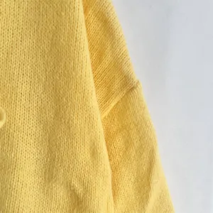 Primer plano detalle de suave tejido de punto amarillo, vista textura jersey estilo.