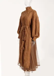 Detailed view of brown cable knit turtleneck sweater dress with mesh skirt and side split.
