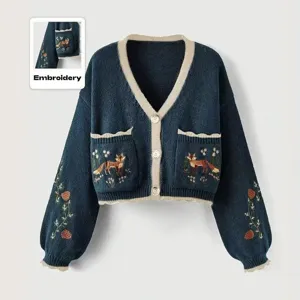 Vue rapprochée de la broderie délicate de renard et de fleurs sur le gilet tricoté.