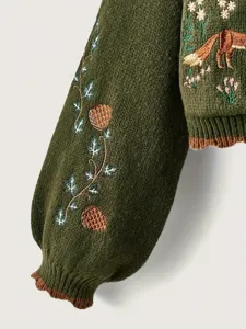 Détail de manche de pull vert, pommes de pin et vignes brodées, vêtement d'hiver confortable.