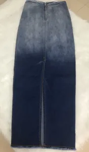 Close-up detail of front zipper, slit design, and frayed hem on gradient wash denim skirt.