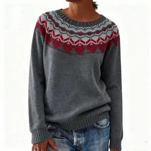 Gros plan sur le pull gris en tricot avec un motif jacquard rouge et gris autour de l'encolure.