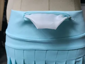 Gros-plan sur les détails de la jupe de yoga plissée taille haute avec poche zippée pratique.