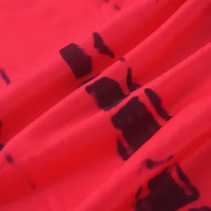 Close up of red and black tie dye dress fabric detail, showing soft texture and pattern.
