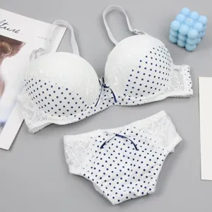 Nahaufnahme des weiß-blauen Pünktchen Spitzen BH und Slip Set mit süßem Schleifendetail.