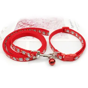 Red pet collar and leash set detail, cute dog pattern, metal hardware and red bell.