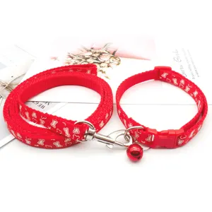 Red dog collar and leash set with bone pattern, metal hardware and small bell for pets.