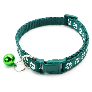 Green pet collar detail showing white paw prints, adjustable strap, metal D-ring and shiny bell.