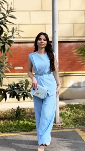 Detailed view of women's solid color sleeveless top and wide-leg trousers outfit outdoor.