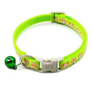 Green pet collar detail, featuring cute cartoon pattern, plastic buckle and metal bell close up.