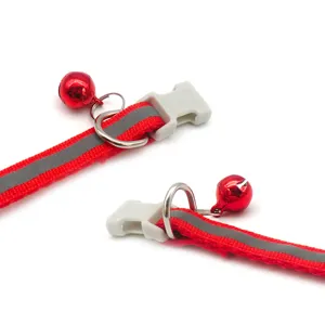 Close-up detail view of red reflective pet collar featuring secure plastic buckle and bell.
