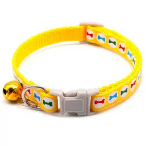 Gedetailleerd opname van gele huisdierenhalsband met botmotief, metalen ring en belletje.