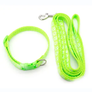 Primo piano dettagliato del set guinzaglio e collare per animali verde vivace con motivi di zampe bianche.