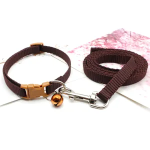 Brown nylon pet collar and leash set featuring a metal bell and buckle, close-up.