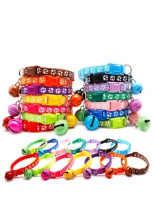 Close-up detail view of colorful nylon pet collars featuring cute paw prints and attached jingle bells.