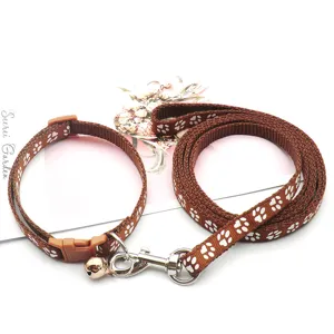 Set guinzaglio e collare per animali marrone con simpatiche impronte di zampe bianche.