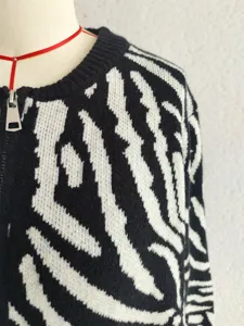 Black and white zebra print knitted cardigan sweater detail view showcasing front zipper closure
